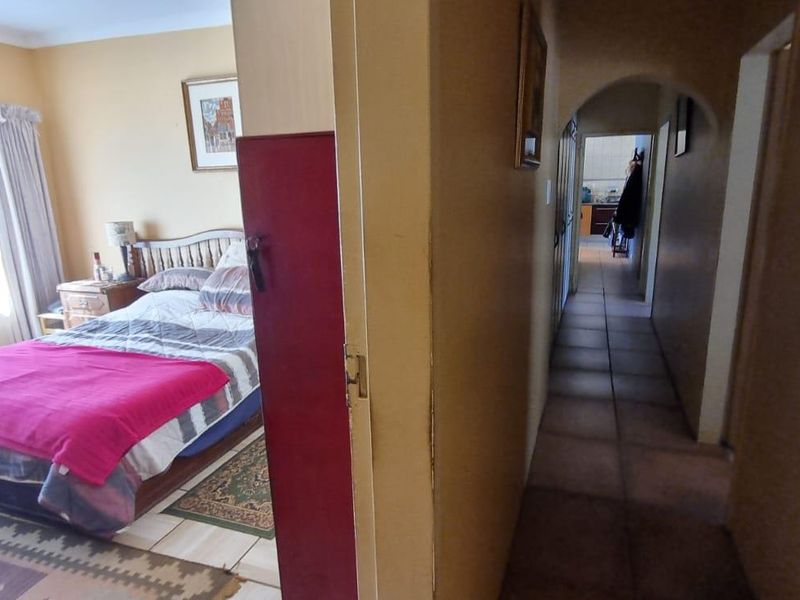 A view from a hallway looking into a bedroom, featuring tiled flooring and arched architectural details.