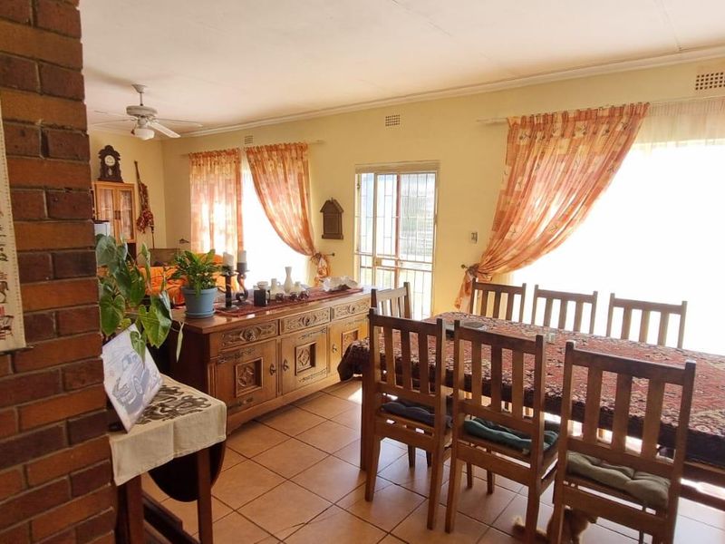 Spacious living and dining area featuring exposed brick accents, tiled flooring, and large windows allowing for ample natural light.