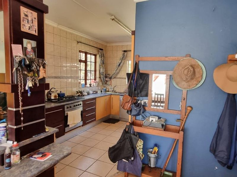 A functional kitchen featuring dark wood cabinetry, tiled splashbacks, and a built-in gas hob and oven, seamlessly connected to the living area.