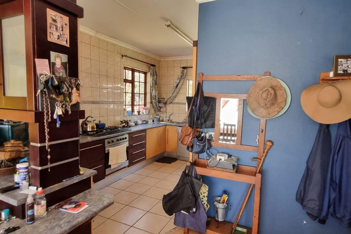 A functional kitchen featuring dark wood cabinetry, tiled splashbacks, and a built-in gas hob and oven, seamlessly connected to the living area.