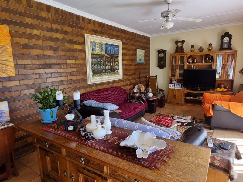 A living room featuring a prominent face-brick feature wall, tiled flooring, and a ceiling fan.