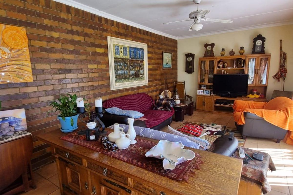 A living room featuring a prominent face-brick feature wall, tiled flooring, and a ceiling fan.