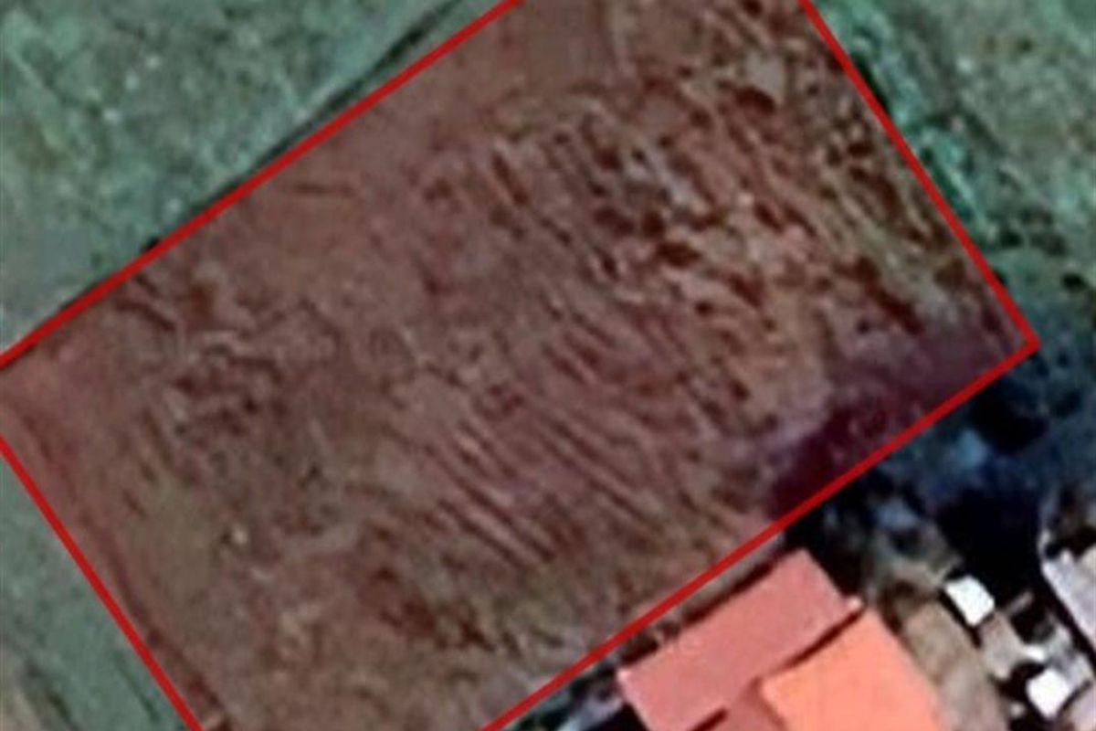 An aerial view of a vacant residential plot of land, clearly outlined in red, showing the site boundaries and surrounding area.