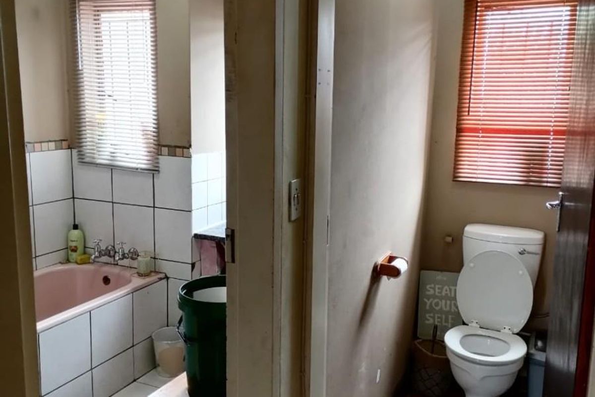 A split-layout bathroom featuring a separate toilet room and a bathroom area with a bathtub and tiled finishes.