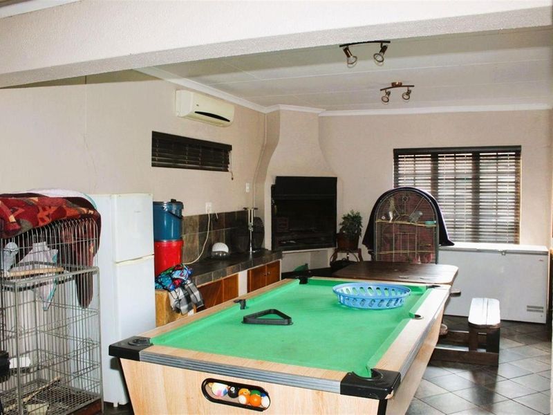A multi-purpose living area featuring a built-in fireplace, tiled flooring, and wall-mounted air conditioning unit, suitable for entertainment or recreational use.