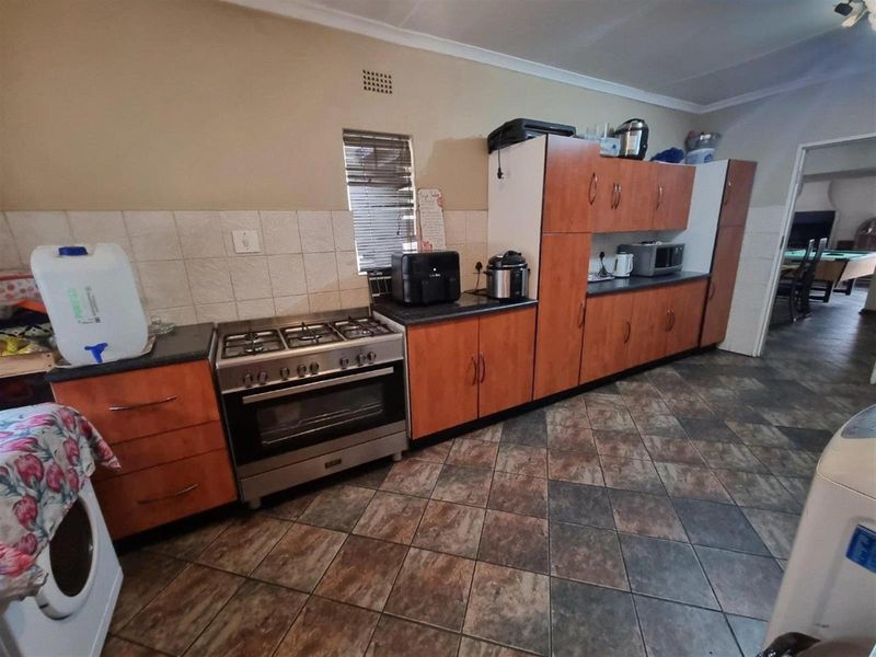 Functional kitchen featuring wood-finish cabinetry, tiled splashbacks, and a built-in gas stove with oven, set against a neutral wall palette.