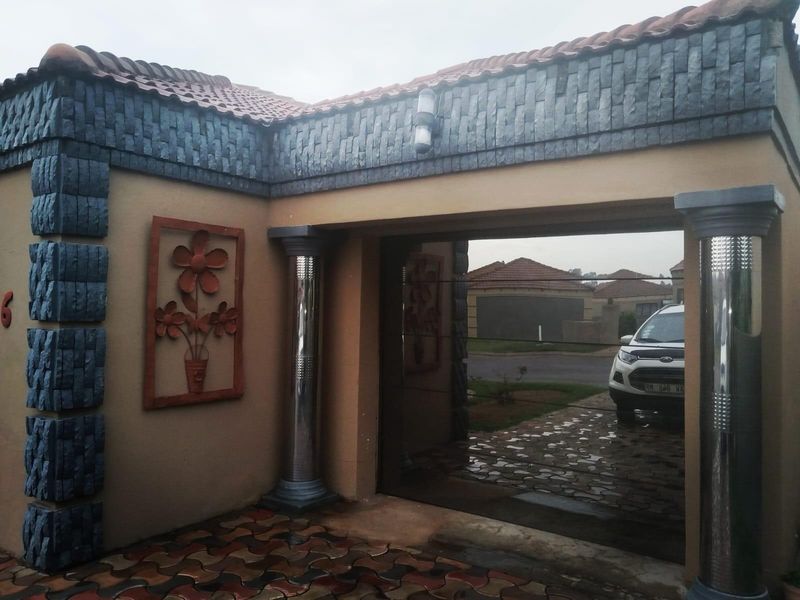 Front facade of the property featuring stone cladding, decorative wall art, stainless steel columns, and a paved driveway entrance.