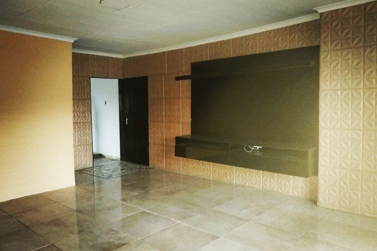 Spacious living area featuring large format floor tiles, textured feature wall cladding, and a built-in media console unit.