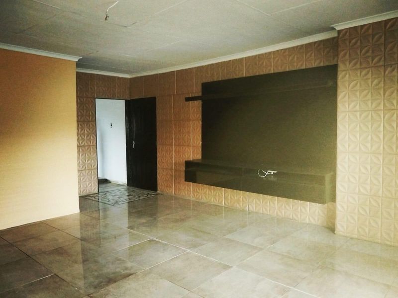 Spacious living area featuring large format floor tiles, textured feature wall cladding, and a built-in media console unit.