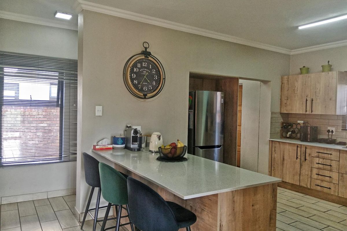 Modern kitchen featuring wood-look cabinetry, stone countertops, a breakfast island, and tiled flooring with integrated appliance space.