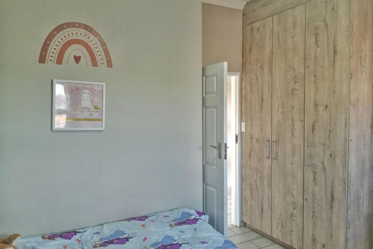 A bedroom featuring built-in wooden cabinetry and tiled flooring, with a doorway leading to an adjacent space.