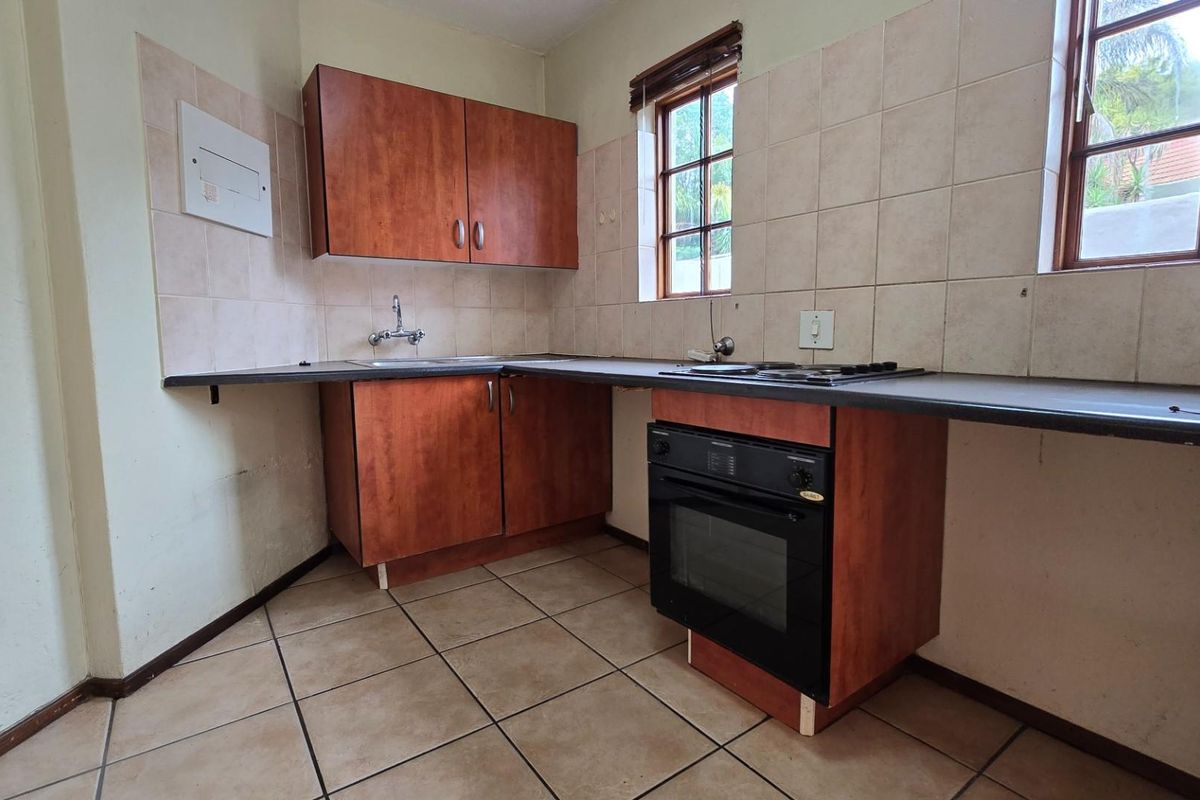 A functional kitchen featuring wood-look cabinetry, tiled splashbacks, a built-in oven, and a hob, offering a practical layout for daily meal preparation.