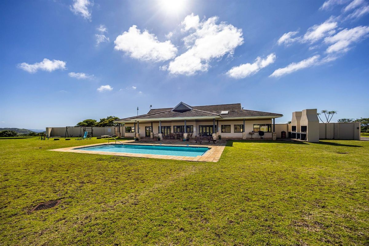 Spacious rear exterior view featuring a well-maintained swimming pool, expansive lawn, and a covered patio area with a built-in outdoor fireplace.