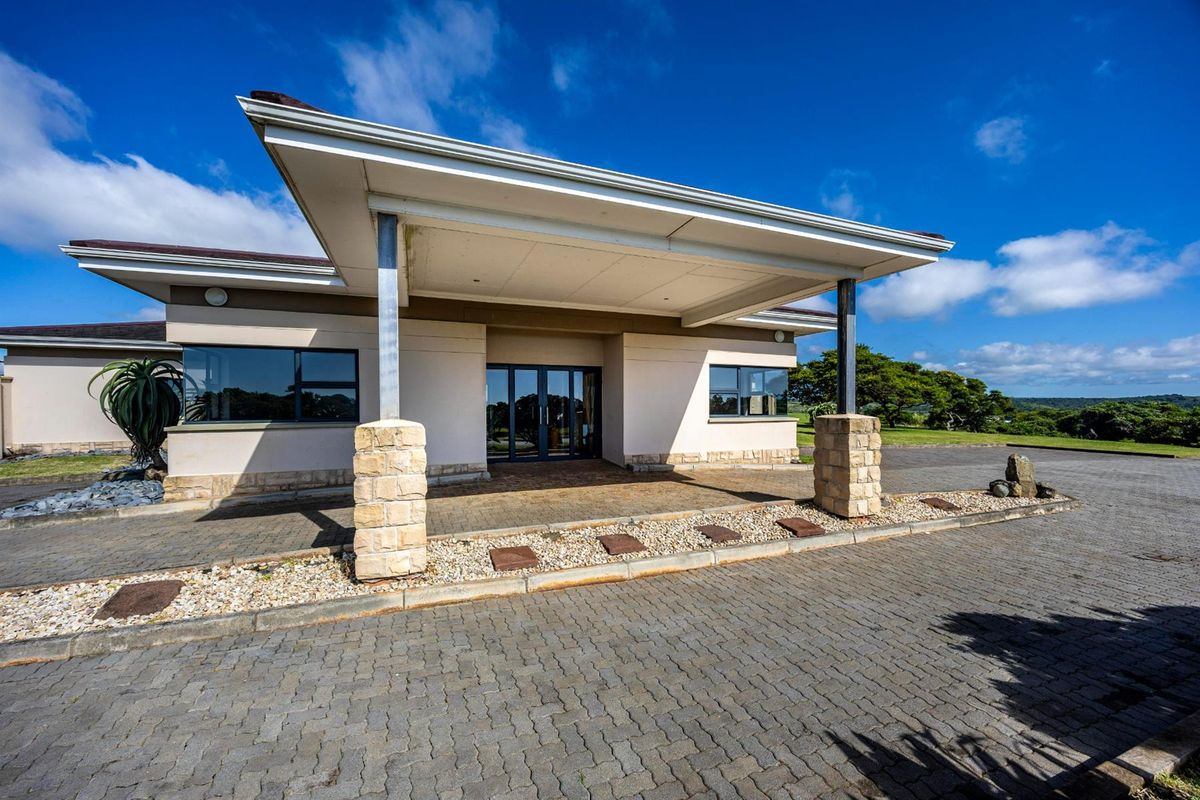 A well-maintained residential property entrance featuring a covered portico, stone-clad pillars, and a paved driveway.