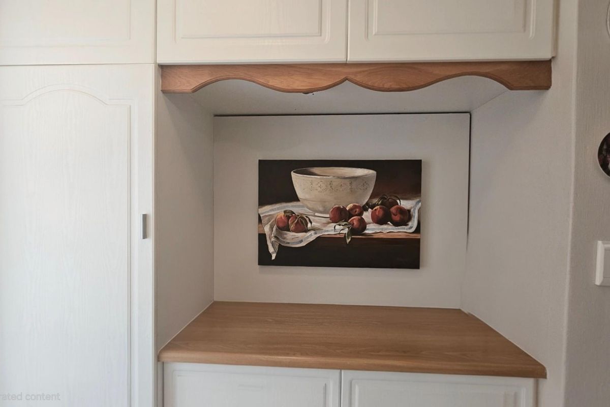 A kitchen nook featuring white cabinetry with wood-toned countertops and a decorative scalloped valance above the workspace.