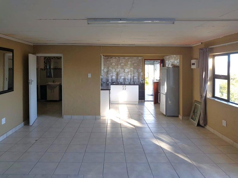 Open plan living and kitchen area featuring tiled flooring, built-in cabinetry, and direct access to an adjacent bathroom and exterior space.