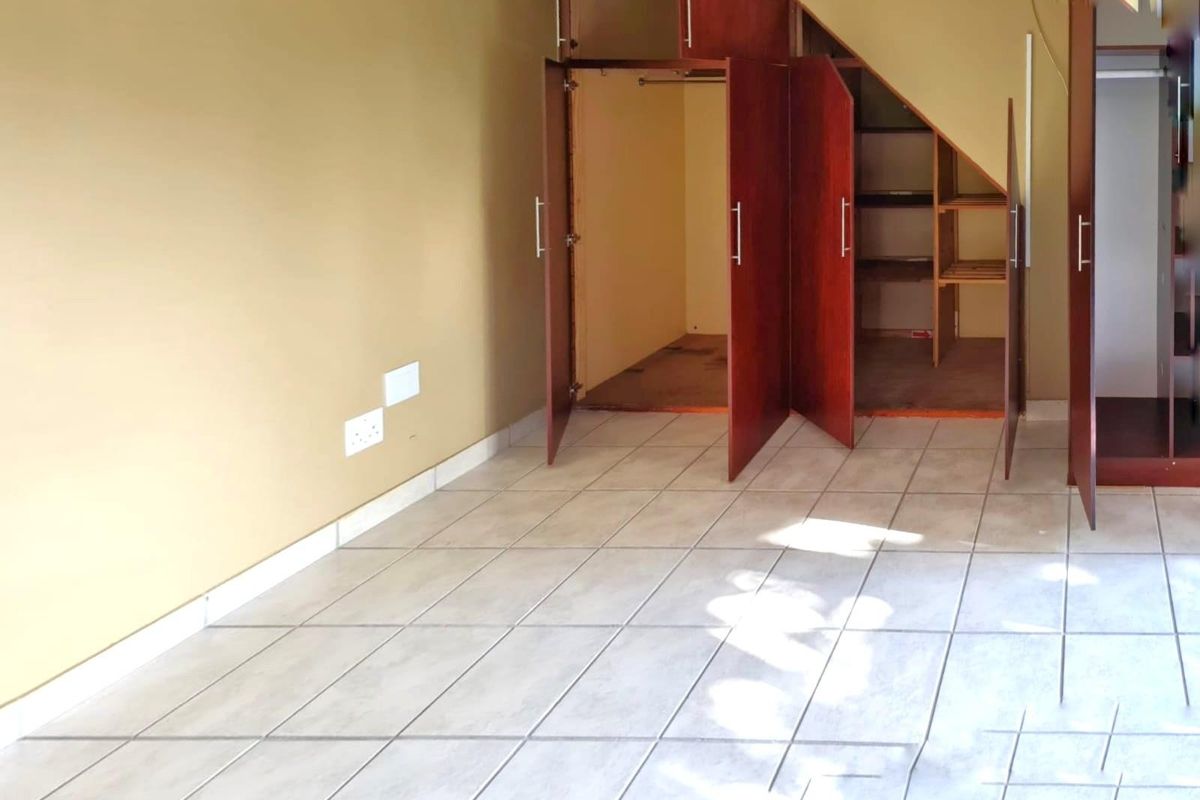 An empty bedroom featuring tiled flooring and built-in under-stair storage cupboards.