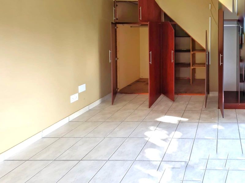 An empty bedroom featuring tiled flooring and built-in under-stair storage cupboards.