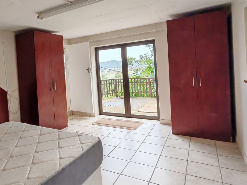 Bedroom featuring built-in cupboards, tiled flooring, and a sliding glass door providing access to an outdoor balcony area.