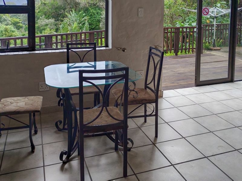 Open plan living area featuring tiled flooring, large windows, and sliding glass doors leading out to a wooden deck.