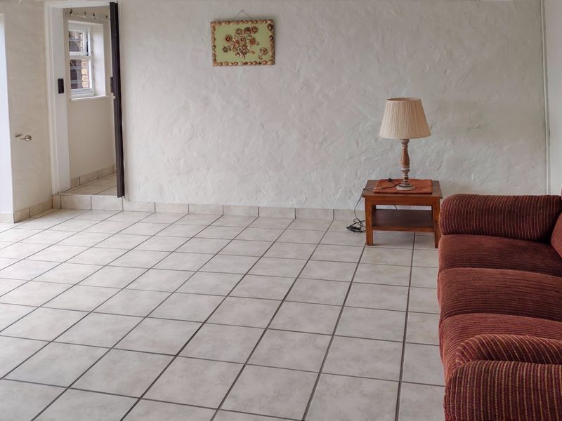 A living area featuring neutral tiled flooring, textured walls, and a sliding glass door providing access to the outdoor space.