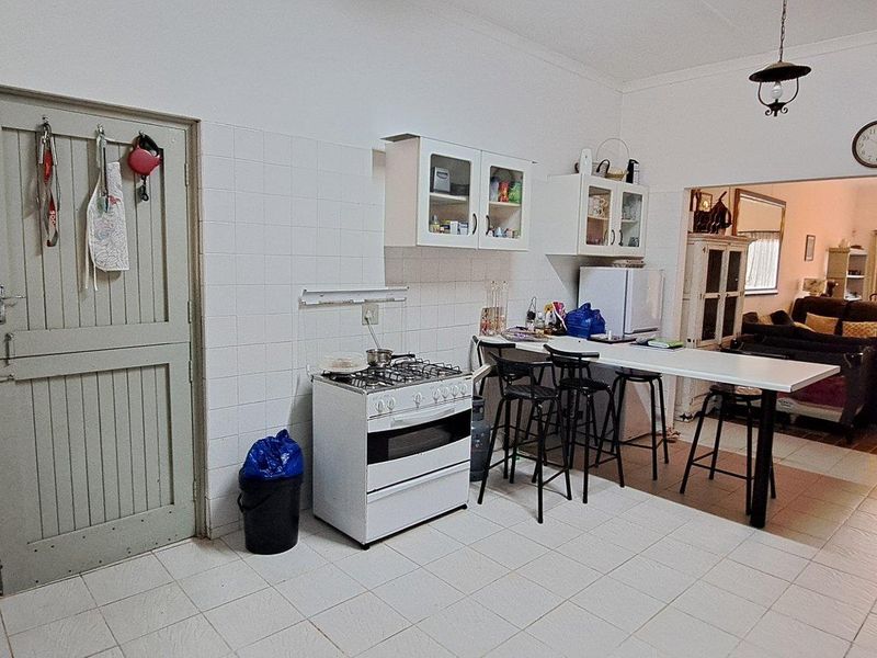 Open-plan kitchen featuring a gas stove, breakfast bar, and tiled flooring, flowing directly into the adjacent living and dining area.