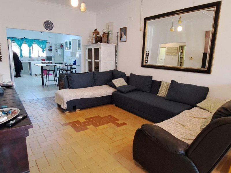 Open plan living area featuring terracotta-style floor tiles, flowing into a connected kitchen space, creating a functional and integrated home layout.