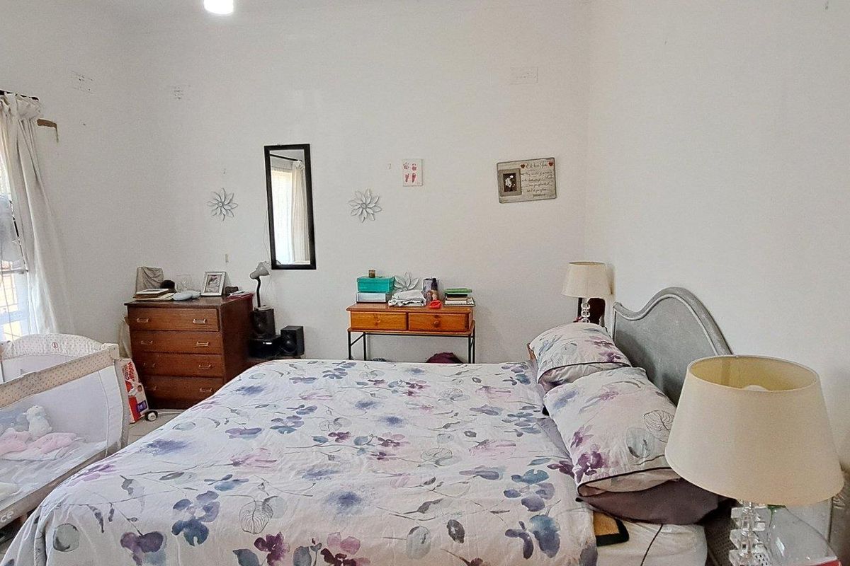A standard bedroom featuring a large window with curtains, providing natural light and a functional layout for a comfortable sleeping space.