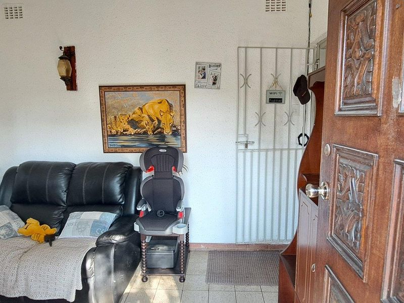 An entry area featuring tiled flooring, a decorative carved wooden door, and a security gate, providing a functional transition space into the home.
