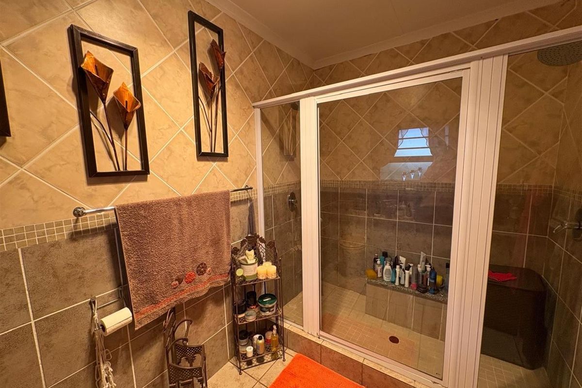 A bathroom featuring a walk-in shower with a glass enclosure, tiled walls, and a built-in shower bench.