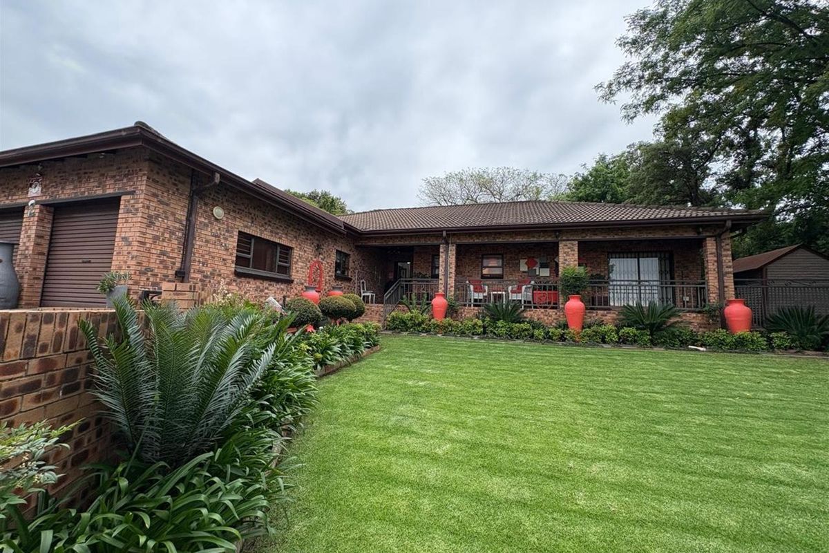A well-maintained brick townhouse featuring a spacious covered patio, manicured lawn, and integrated garage, offering a classic and durable exterior aesthetic.