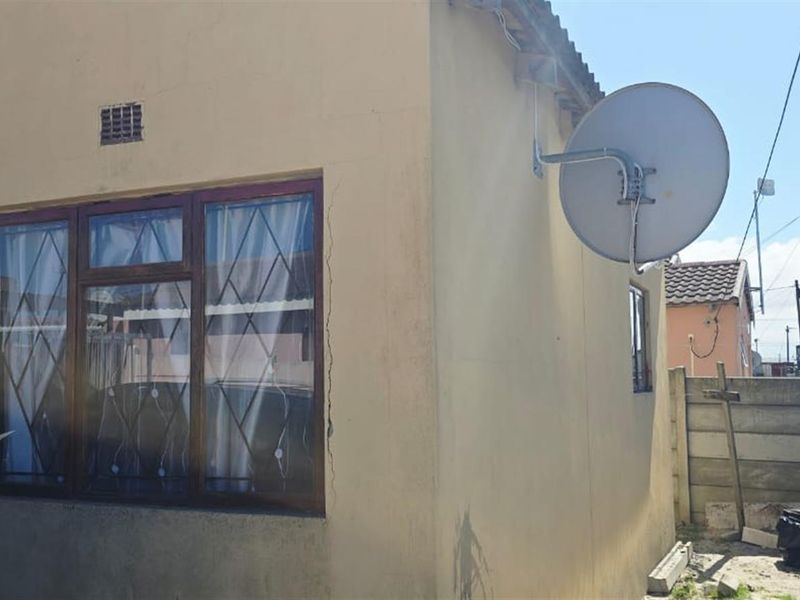 Exterior view of the property facade featuring a large window, satellite dish, and surrounding precast concrete boundary walling.