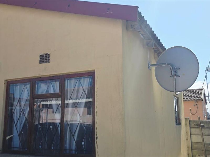 Exterior view of the property facade featuring a satellite dish, security window bars, and visible structural wall cracking.