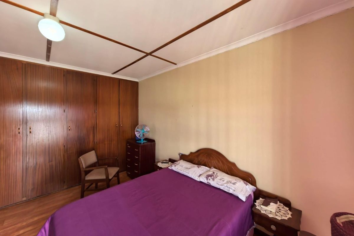 A bedroom featuring built-in wooden cupboards and laminate flooring, offering a functional space with classic cabinetry.