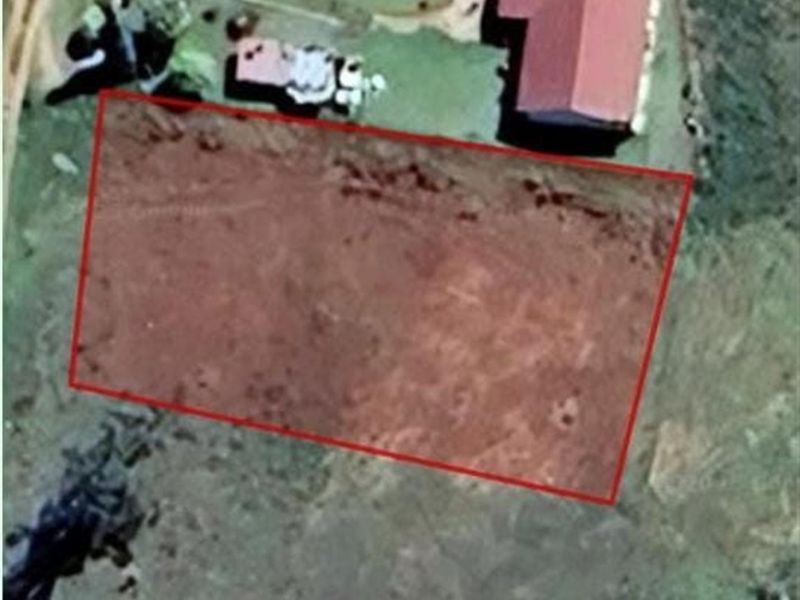 An aerial view of a vacant residential plot of land, highlighted with a red boundary outline.
