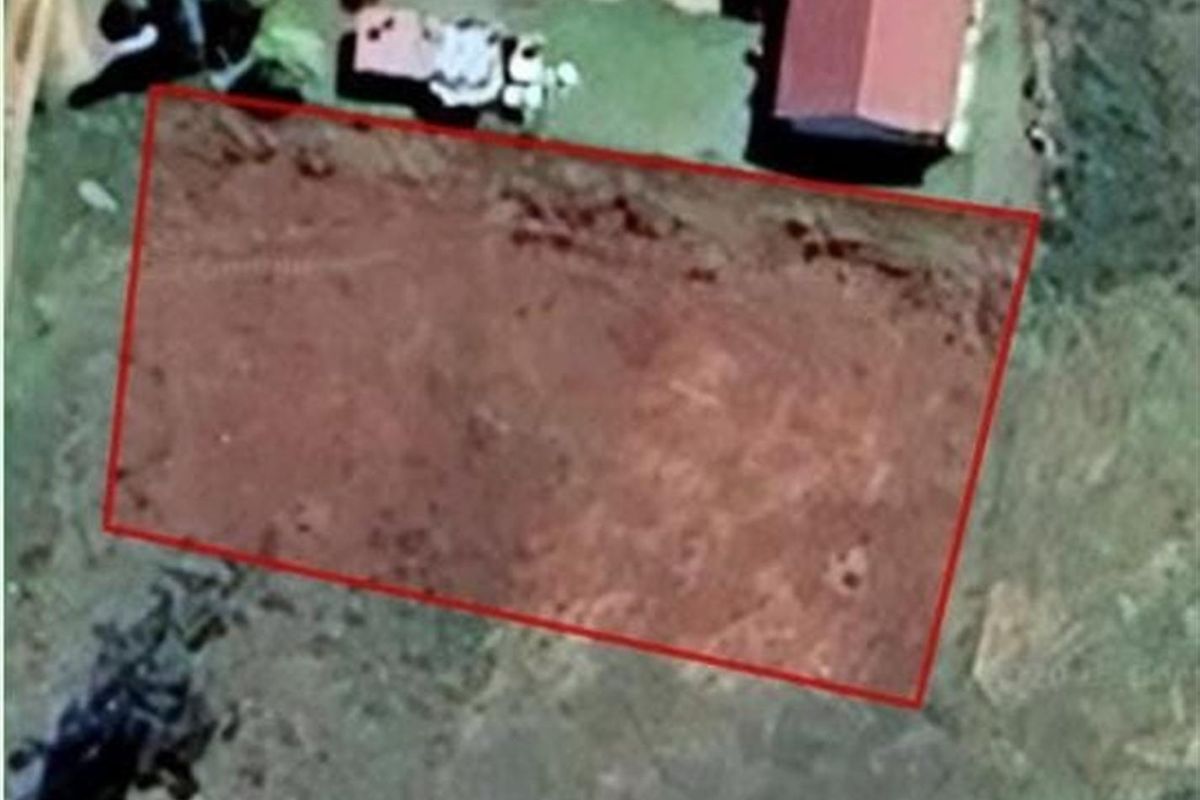 An aerial view of a vacant residential plot of land, highlighted with a red boundary outline.