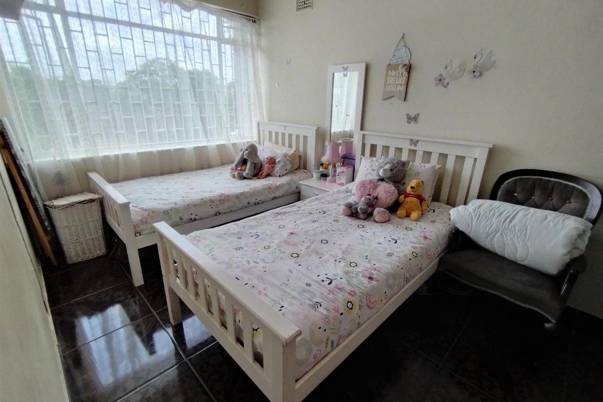 A bedroom featuring large windows with security bars and dark tiled flooring.