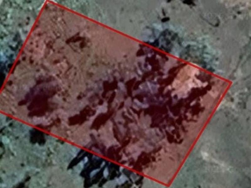 An aerial satellite view of a vacant residential land plot highlighted with a red boundary overlay.