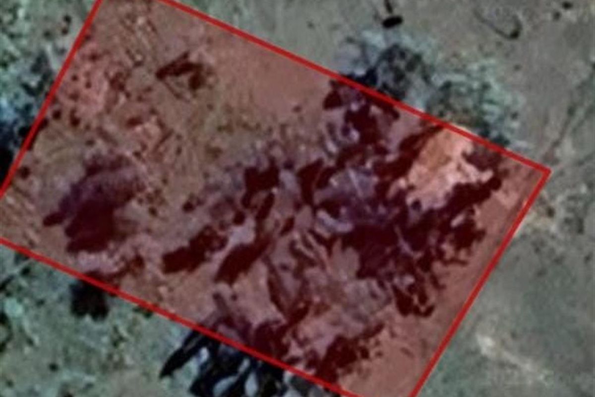 An aerial satellite view of a vacant residential land plot highlighted with a red boundary overlay.