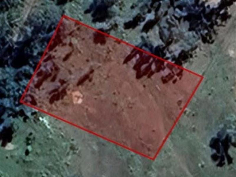 An aerial view of a vacant residential land plot with a red boundary overlay indicating the property perimeter.