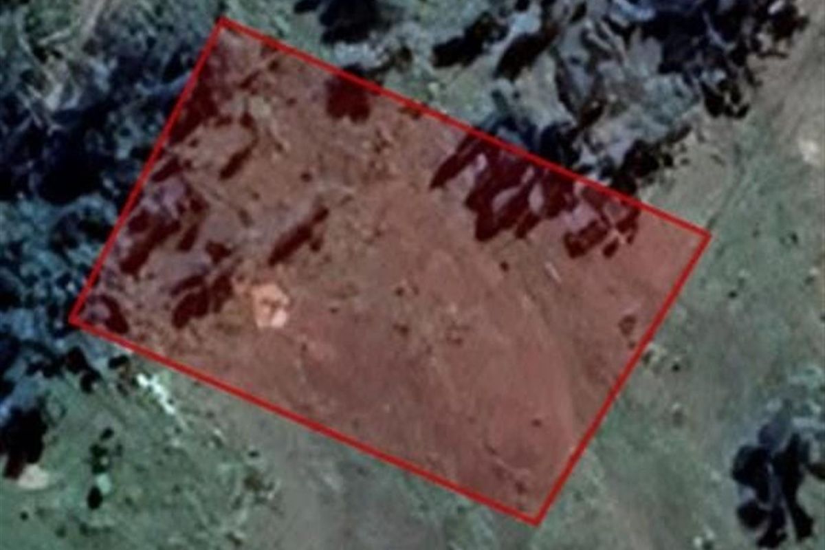 An aerial view of a vacant residential land plot with a red boundary overlay indicating the property perimeter.