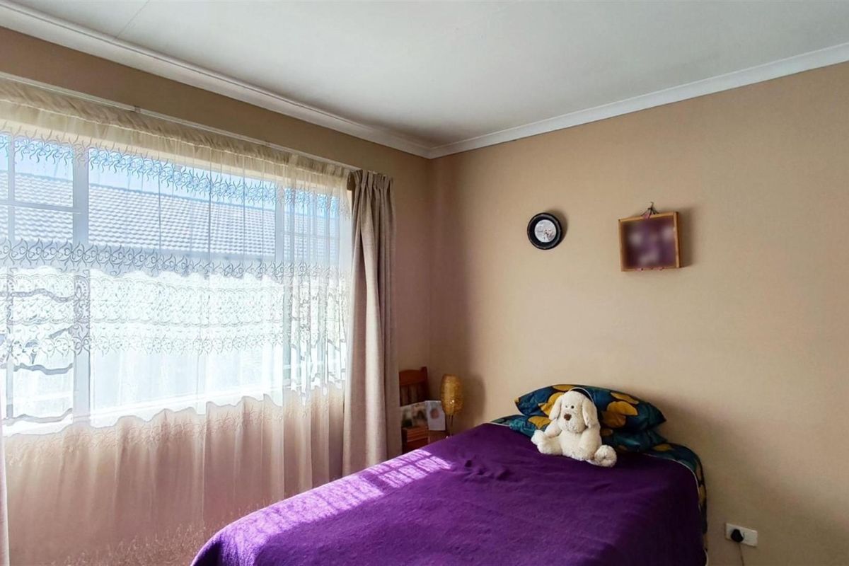 A bedroom featuring neutral wall tones, a large window with natural light, and coved ceiling detailing.
