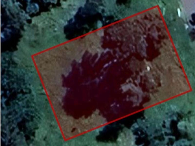 An aerial view of a vacant residential plot of land, highlighted with a red boundary outline.