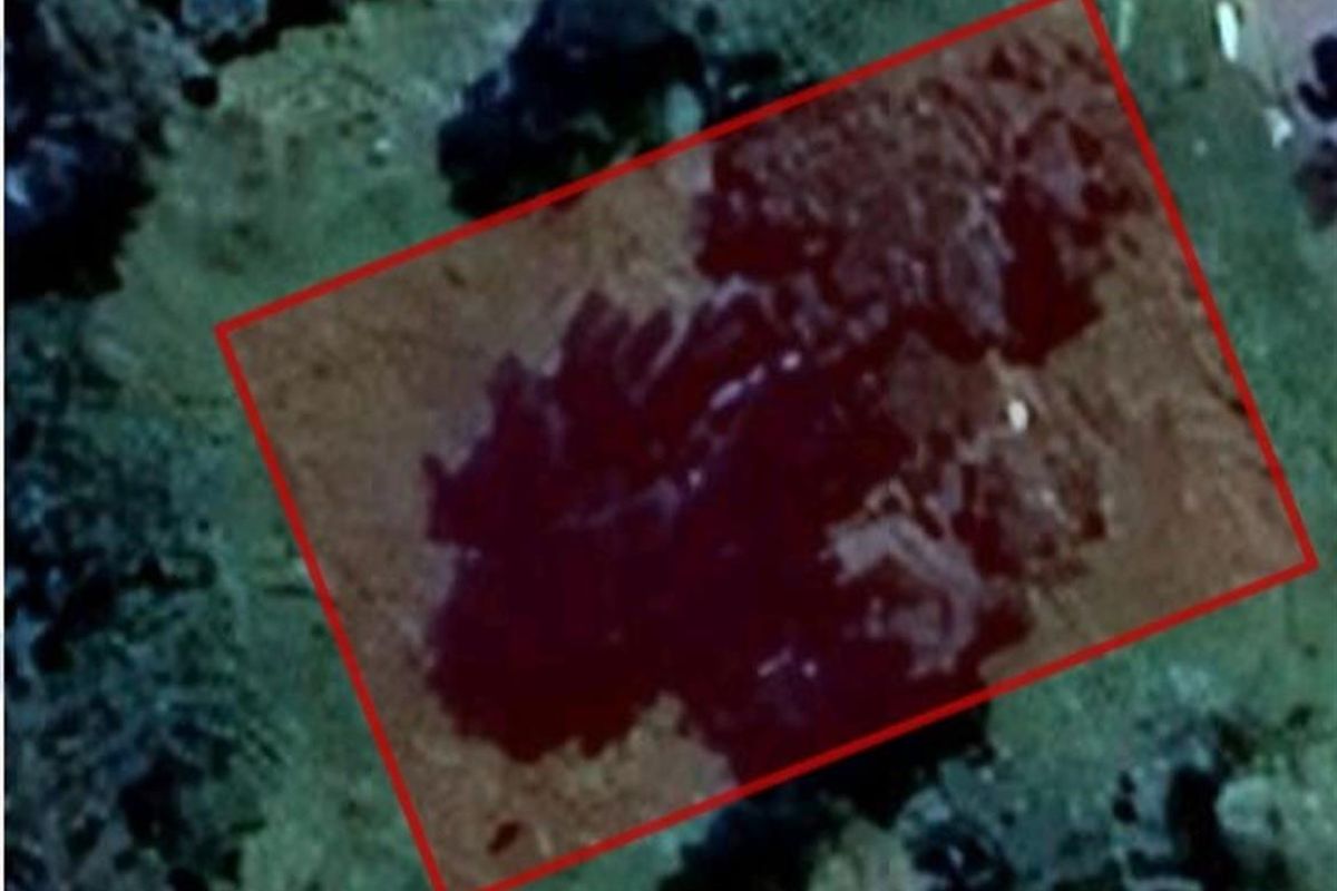 An aerial view of a vacant residential plot of land, highlighted with a red boundary outline.