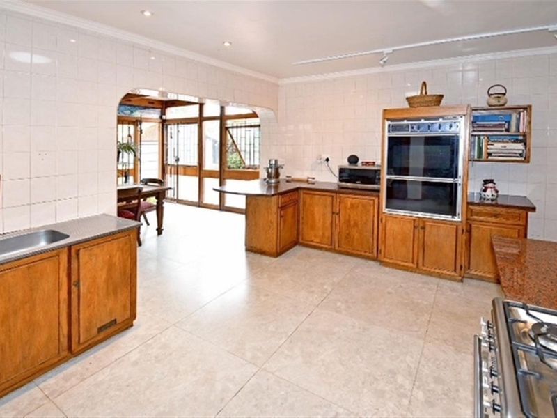 Spacious kitchen featuring wooden cabinetry, built-in double oven, gas hob, and tiled finishes, offering a functional layout with potential for modern updates.