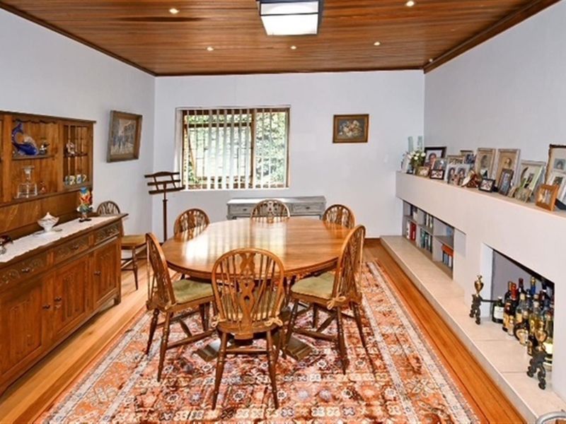 A dining room featuring a timber-clad ceiling, hardwood flooring, and a built-in fireplace with integrated shelving.