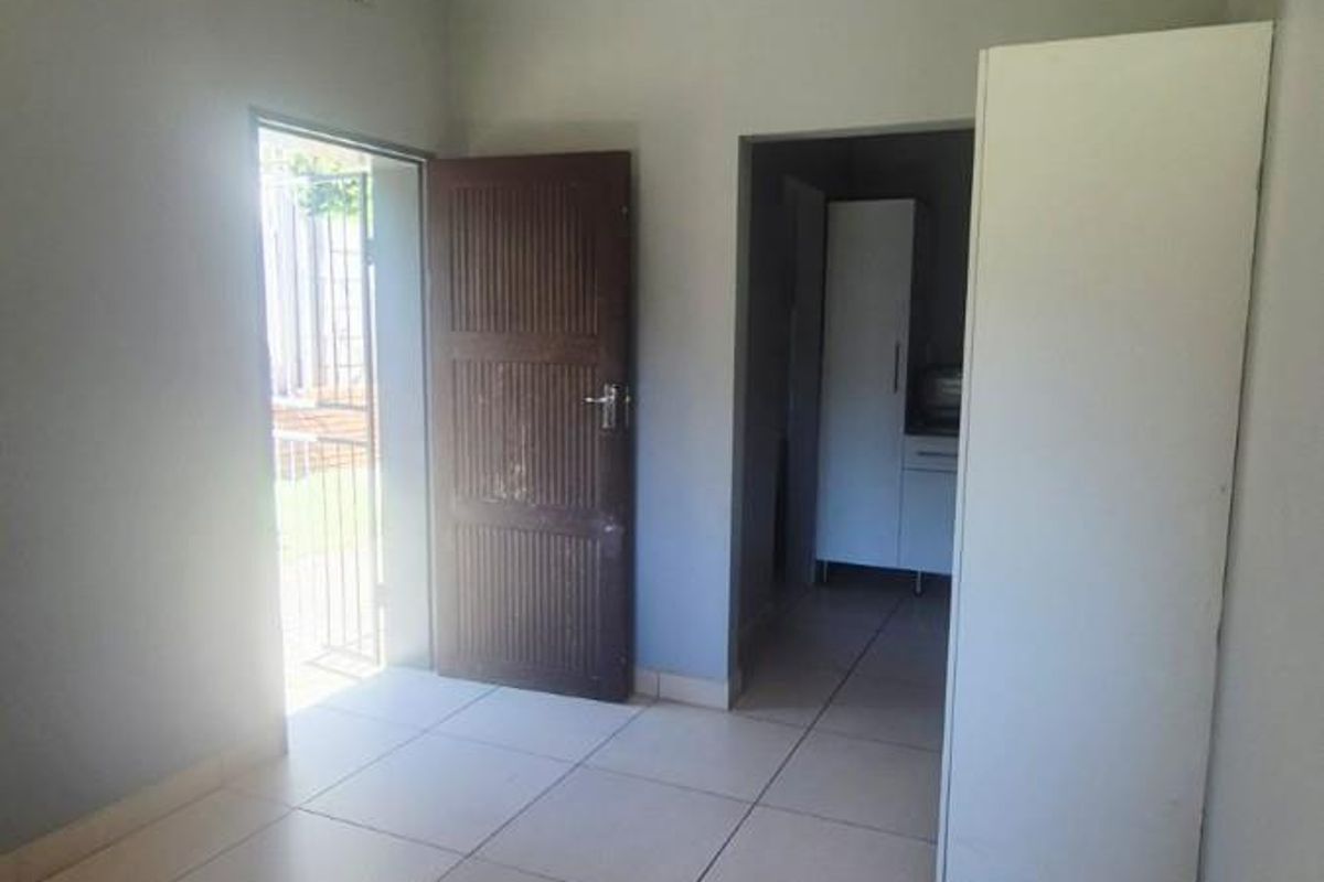 A functional hallway space featuring neutral tiled flooring, a ceiling-mounted light fixture, and access to an adjacent room.
