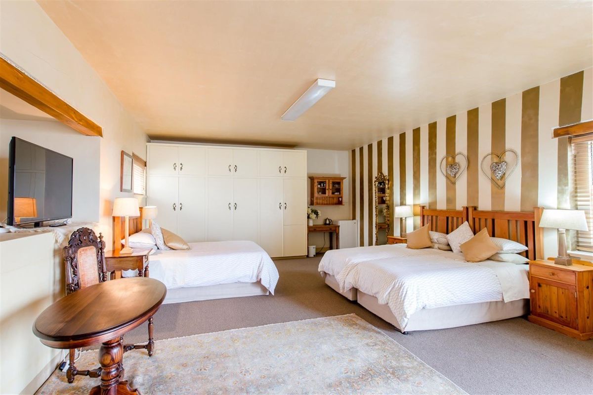 Spacious bedroom featuring built-in cupboards, carpeted flooring, and a functional layout with ample space for multiple beds.