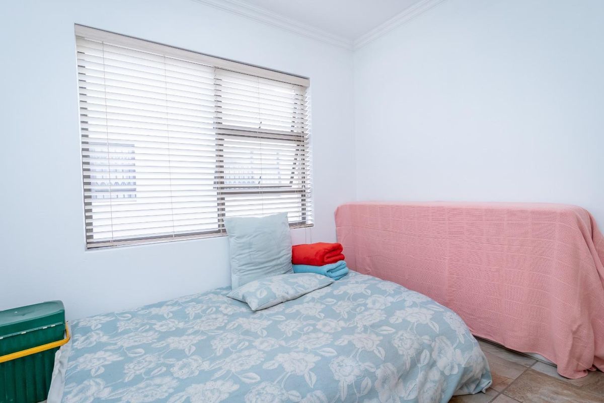 A simple bedroom featuring tiled flooring, a window with fitted blinds, and crown molding.