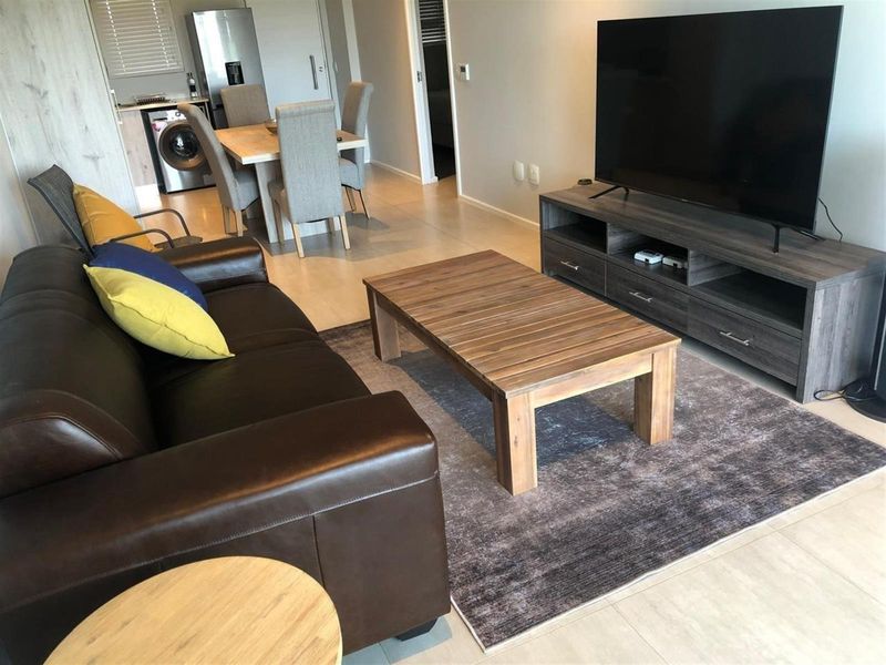 Open-plan living and dining area featuring tiled flooring and an integrated kitchen space with laundry facilities.